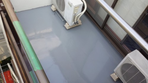 Balcony with a blue-gray floor, metal railing, and two outdoor air conditioning units on small pads near glass doors.