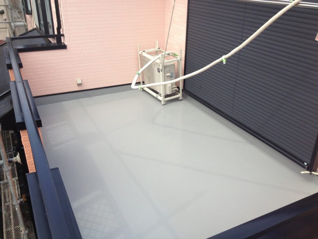 Rooftop balcony with pink brick walls, a metal-framed air conditioner unit, and a curved white pipe spanning the area.