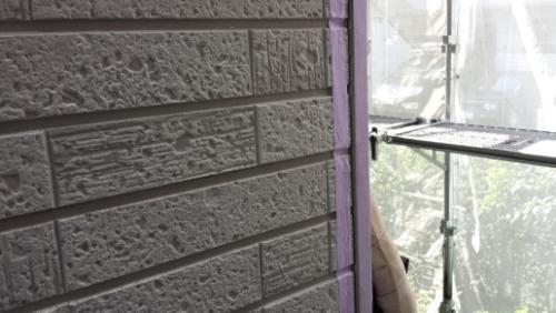20130827-092417 | 外壁塗装は神奈川県横浜市の塗装職人 Purple painter's tape along a brick exterior wall with scaffolding visible on the right, indicating ongoing painting work.