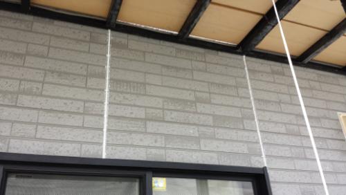 20130828-133619 | 外壁塗装は神奈川県横浜市の塗装職人 Exterior grey brick wall with a black-framed window and white cords hanging from the eave.