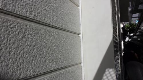 20130831-161036 | 外壁塗装は神奈川県横浜市の塗装職人 Exterior wall of a building with textured horizontal siding and a diagonal shadow on a white panel near the edge of a doorway or balcony area.