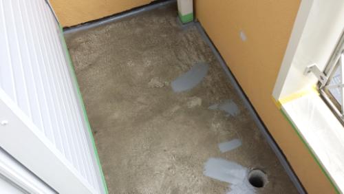 20130912-123349 | 外壁塗装は神奈川県横浜市の塗装職人 Concrete balcony floor under repair with gray epoxy patches and a floor drain, edges taped for painting/renovation, doorway open