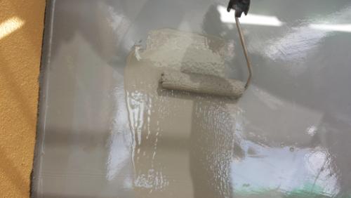 20130913-103541 | 外壁塗装は神奈川県横浜市の塗装職人 A paint roller applying light gray paint to a smooth wall, showing a wet glossy finish.