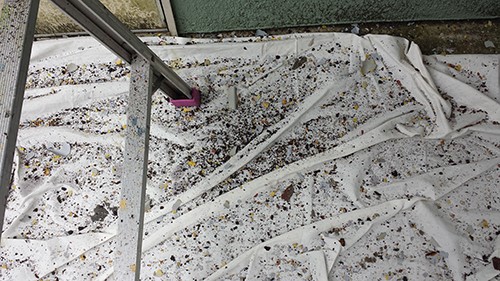 koushin_09kerenks | 外壁塗装は神奈川県横浜市の塗装職人 White tarp spread on the ground outside, dirty with dirt and small rocks, with metal scaffold legs and a pink/purple tool resting on it.