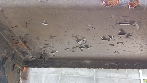 koushin_29hakuri | 外壁塗装は神奈川県横浜市の塗装職人 Close-up of a rusted metal beam with peeling black paint and chipped edges.