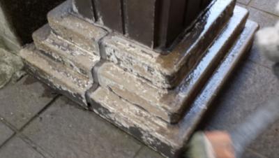 Close-up of a weathered stone pedestal base with stacked blocks and chipped corners around a metal column.