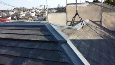 Rooftop with dark slate shingles and scaffolding, overlooking a city neighborhood.