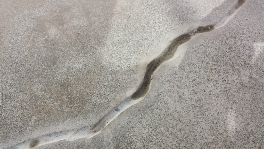 Aerial view of a pale, meandering crack across a sandy surface