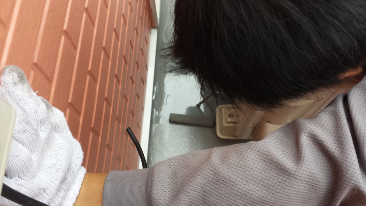 METADATA-START | 外壁塗装は神奈川県横浜市の塗装職人 Person in a gray shirt wearing a white glove, crouched beside a brick wall near an outdoor electrical outlet.