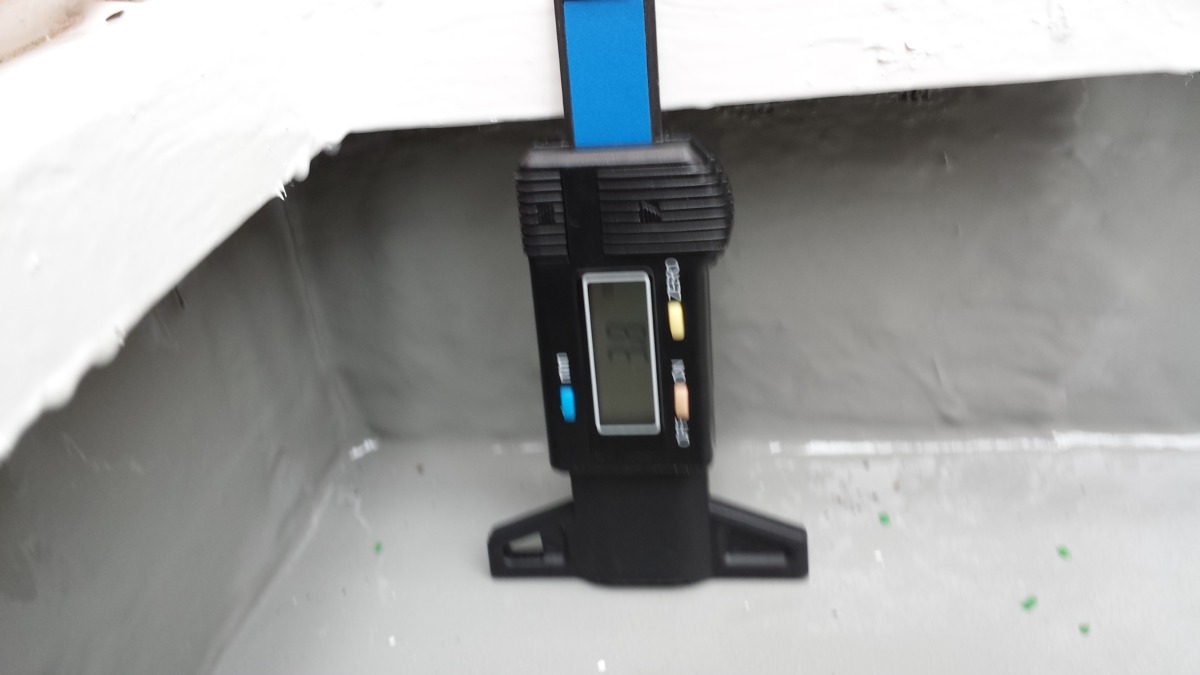 METADATA-START | 外壁塗装は神奈川県横浜市の塗装職人 Digital force gauge attached to a blue strap, hanging in a concrete/workspace area; display visible but unreadable from distance.