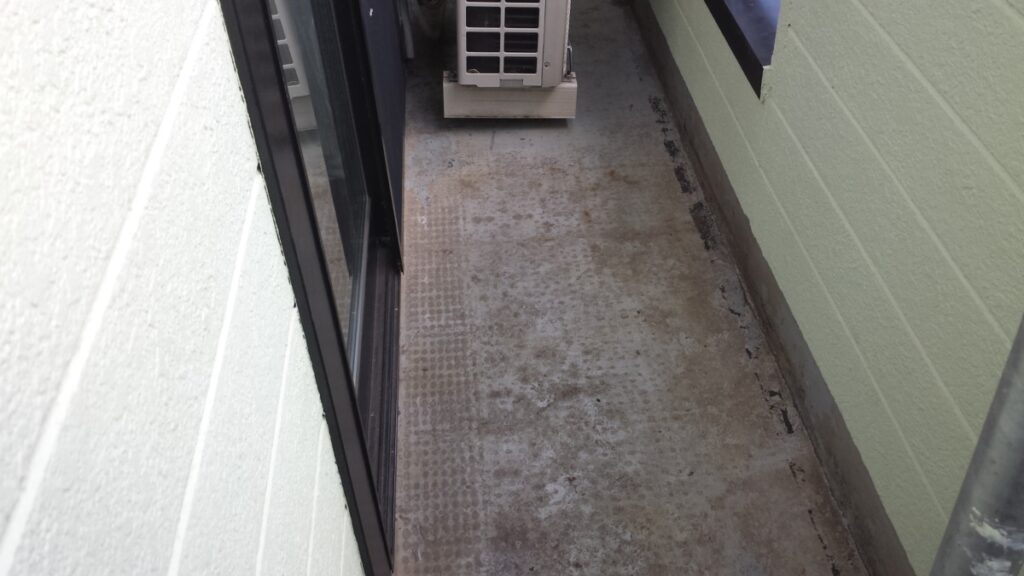METADATA-START | 外壁塗装は神奈川県横浜市の塗装職人 Narrow concrete balcony with pale green walls and an outdoor air conditioner unit at the far end.