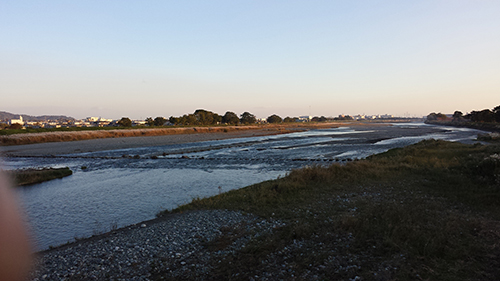 koushin_18kawa | 外壁塗装は神奈川県横浜市の塗装職人 A shallow river or tidal estuary at dusk, with grassy banks and a distant town along the horizon