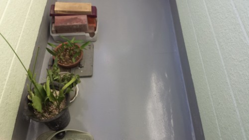 koushin_topcoat3 | 外壁塗装は神奈川県横浜市の塗装職人 Narrow balcony corner with several potted plants along the left edge and a small stack of bricks on a tray.