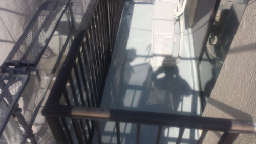 koushin_20140323-0943561 | 外壁塗装は神奈川県横浜市の塗装職人 Shadow of a person taking a photo visible on a glass balcony floor, with dark metal railing and surrounding walls.
