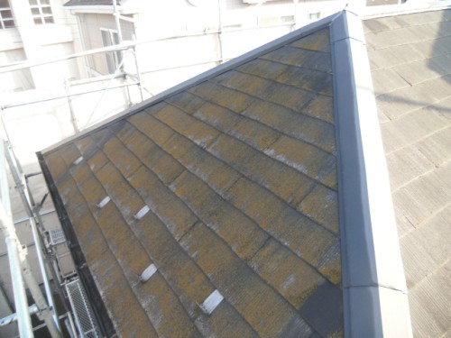 koushin_CIMG1141-1 | 外壁塗装は神奈川県横浜市の塗装職人 Angle view of a sloped roof with mossy brown shingles, metal edge flashing, and surrounding buildings
