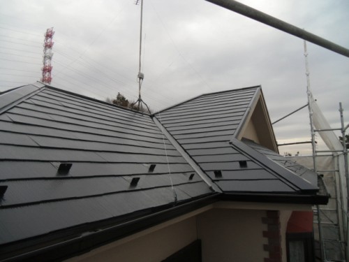 koushin_CIMG1247-1 | 外壁塗装は神奈川県横浜市の塗装職人 New dark metal-tiled roof under construction with scaffolding and a lifting crane cable overhead.