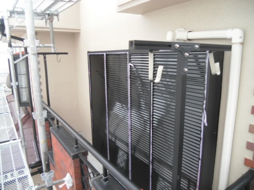 koushin_CIMG1249-1 | 外壁塗装は神奈川県横浜市の塗装職人 Construction scaffolding beside a building with a black louvered vent panel and white PVC pipes attached to the wall