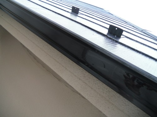 koushin_CIMG125-1 | 外壁塗装は神奈川県横浜市の塗装職人 Close-up of a metal roof flashing along a white stucco wall, viewed from below.
