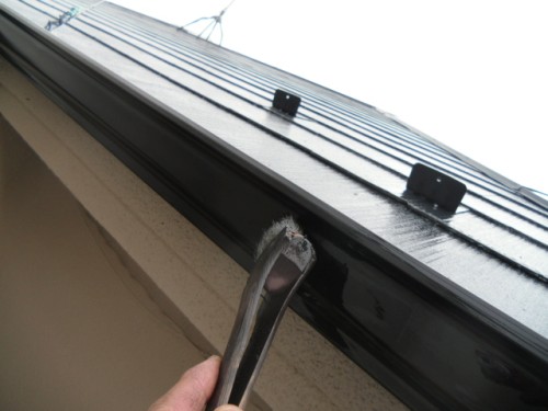 koushin_CIMG1251-1 | 外壁塗装は神奈川県横浜市の塗装職人 Close-up of a hand prying weatherstripping from a metal window frame on a building exterior.