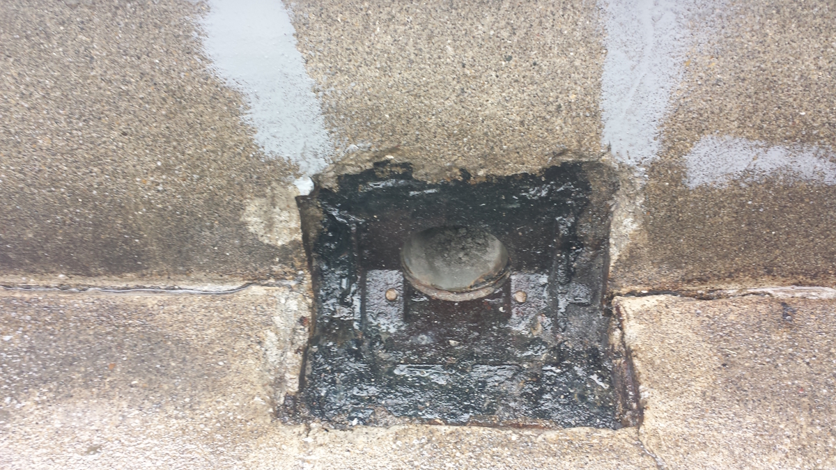 METADATA-START | 外壁塗装は神奈川県横浜市の塗装職人 Square recessed drain with a round cap in a wet, tar-covered concrete area on a sidewalk.