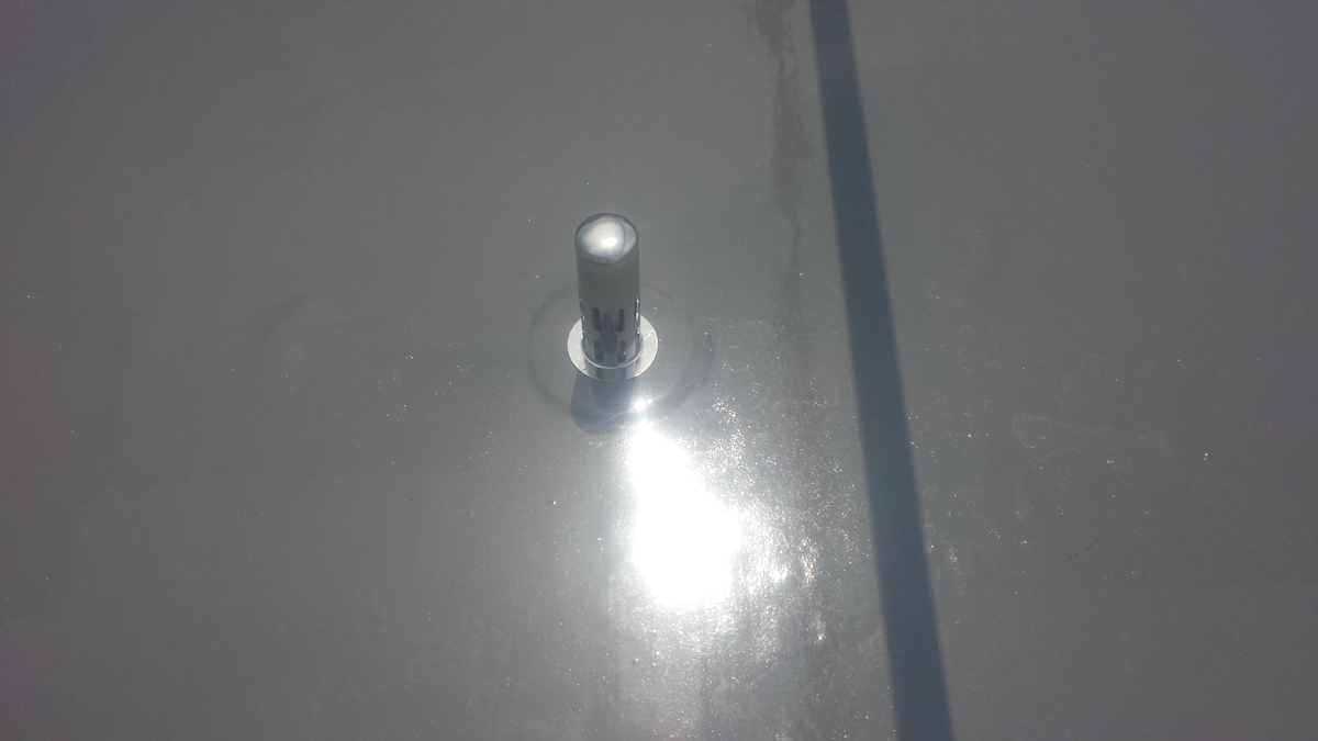 METADATA-START | 外壁塗装は神奈川県横浜市の塗装職人 Metal cylindrical post with a circular base on a glossy gray surface, with bright sun glare and a long shadow nearby