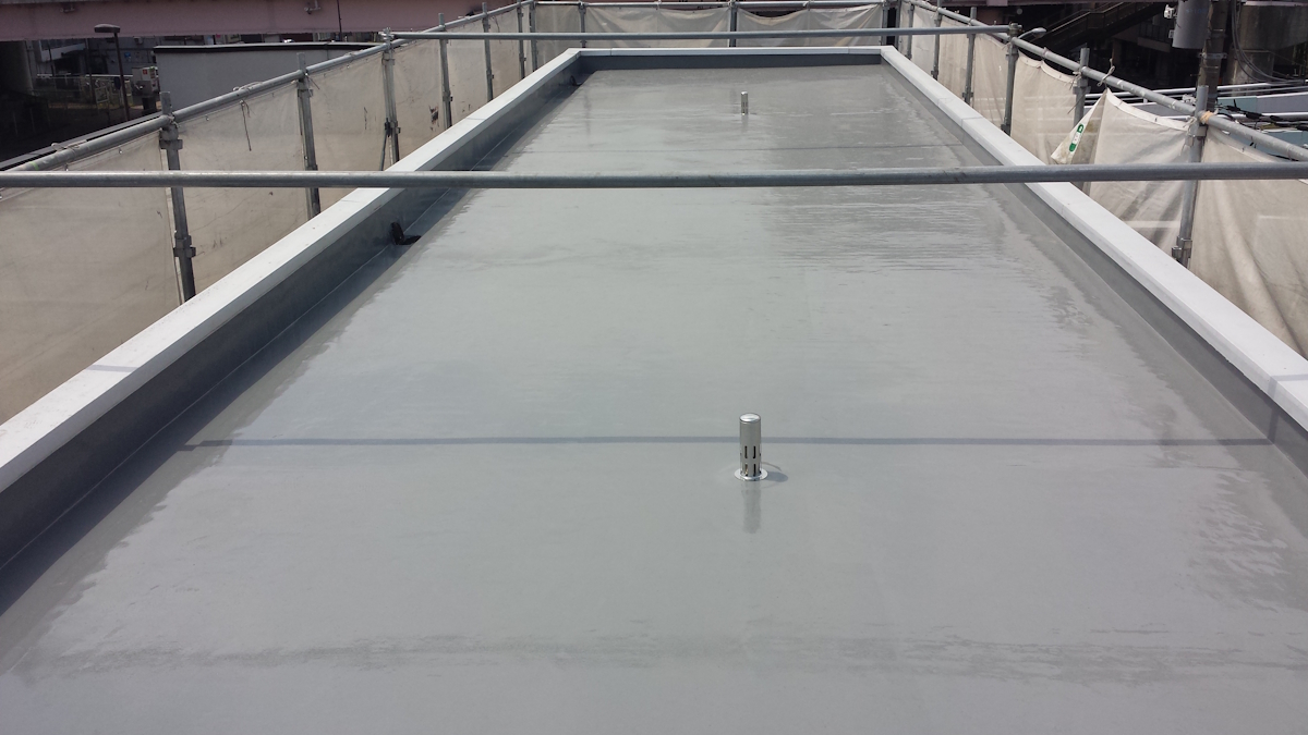 METADATA-START | 外壁塗装は神奈川県横浜市の塗装職人 Flat, light-gray roof with a glossy waterproof coating and small vent pipes, surrounded by scaffolding and safety railings on all sides