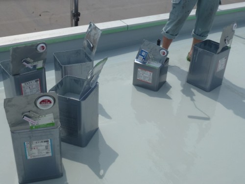 P1030275-1 | 外壁塗装は神奈川県横浜市の塗装職人 Multiple metal refrigerant canisters with gauges and labels on a flat rooftop, a worker's legs visible in the background.