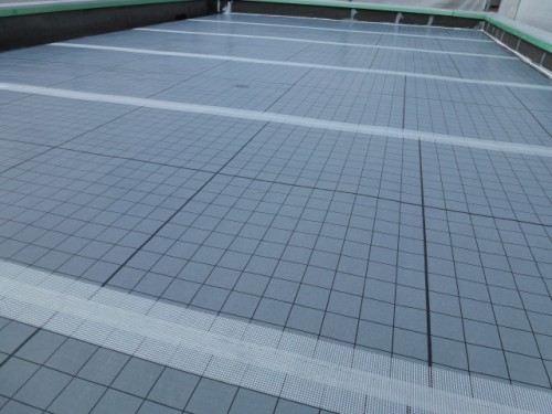 koushin_P1030137-1 | 外壁塗装は神奈川県横浜市の塗装職人 Flat rooftop or terrace with grey square tiles, separated by white lines, and light drainage channels along the surface edge