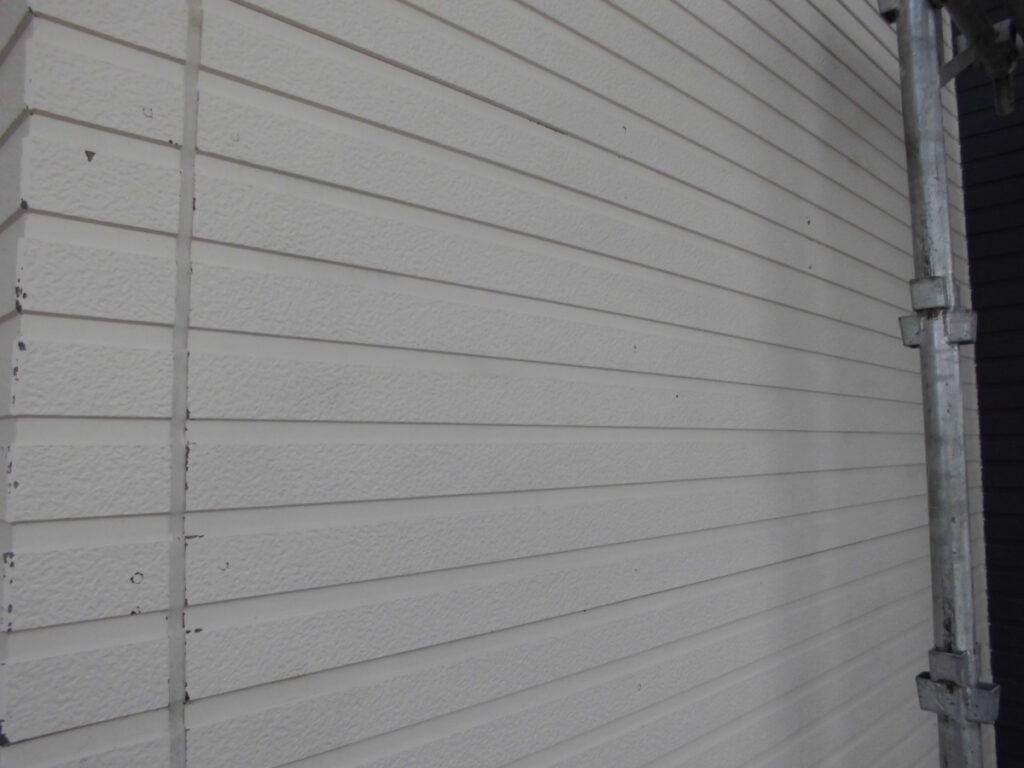 White horizontal vinyl siding on an exterior wall with scaffolding visible on the right side.