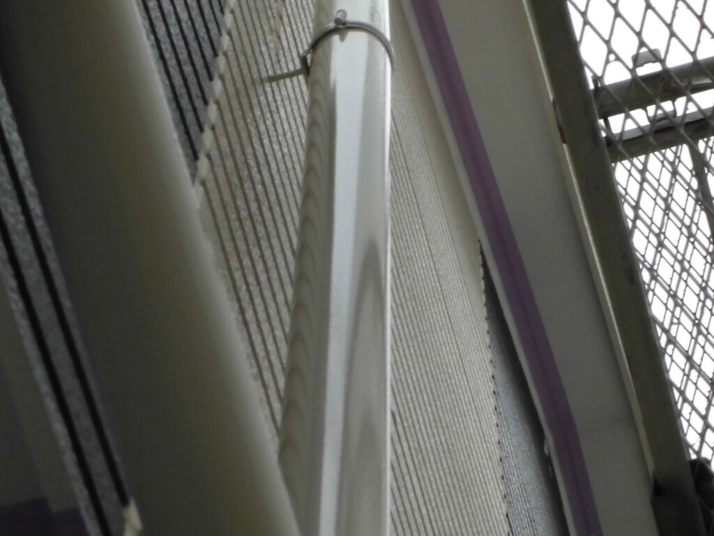 Close-up of a metal handrail beside a wire mesh barrier in a stairwell, viewed from an angled perspective.