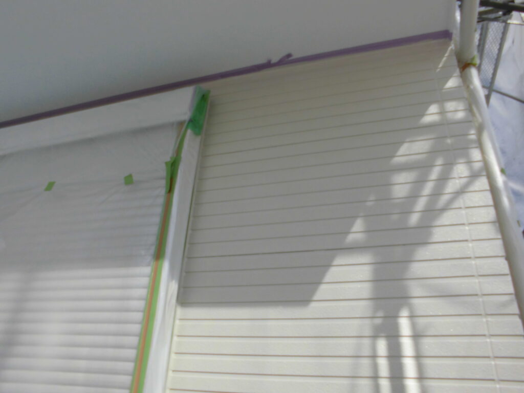 White exterior wall with horizontal siding, masking tape along a doorway, likely under painting/repair.