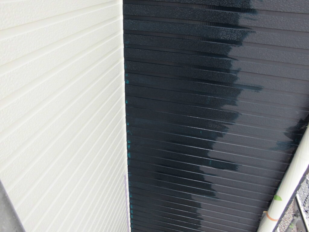 White corrugated wall on the left meets a dark blue painted panel on the right, showing wet paint streaks; a taped PVC pipe is in the lower corner.
