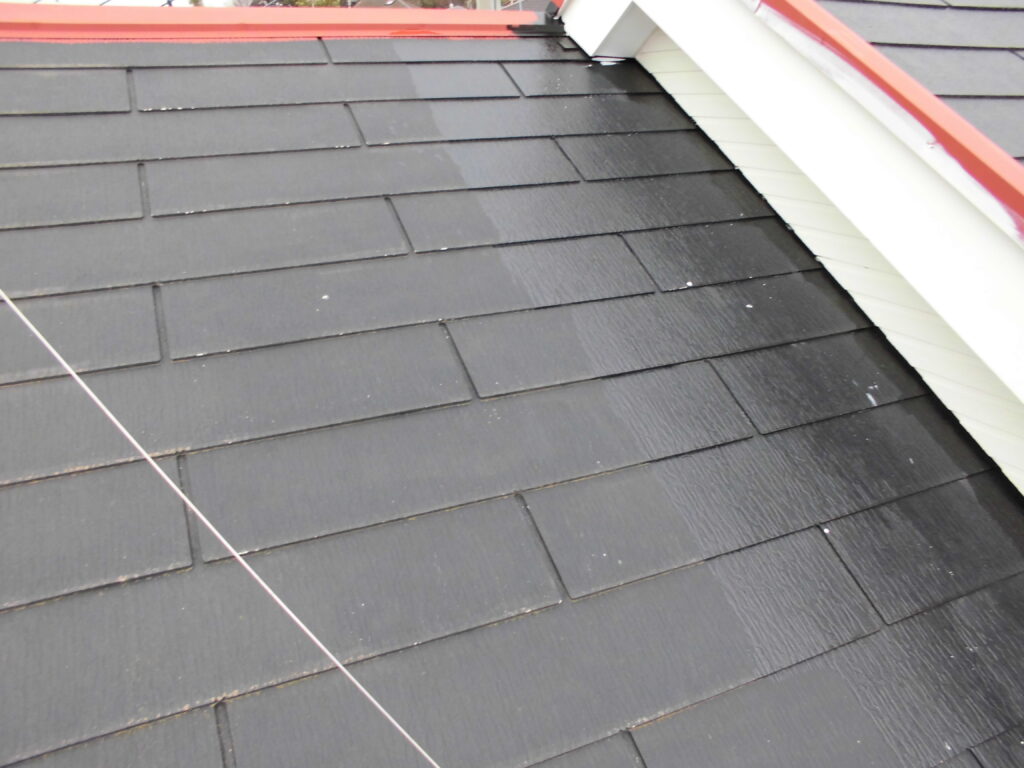 Black tiled roof viewed from above with white siding and red edge trim at the peak area