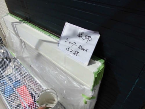 Outdoor air conditioner unit wrapped in plastic with a handwritten sign taped to it.