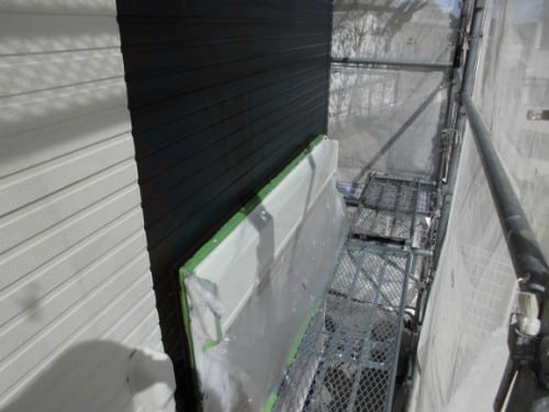 Scaffolding beside a house; green taped plastic cover protecting a window edge during painting.