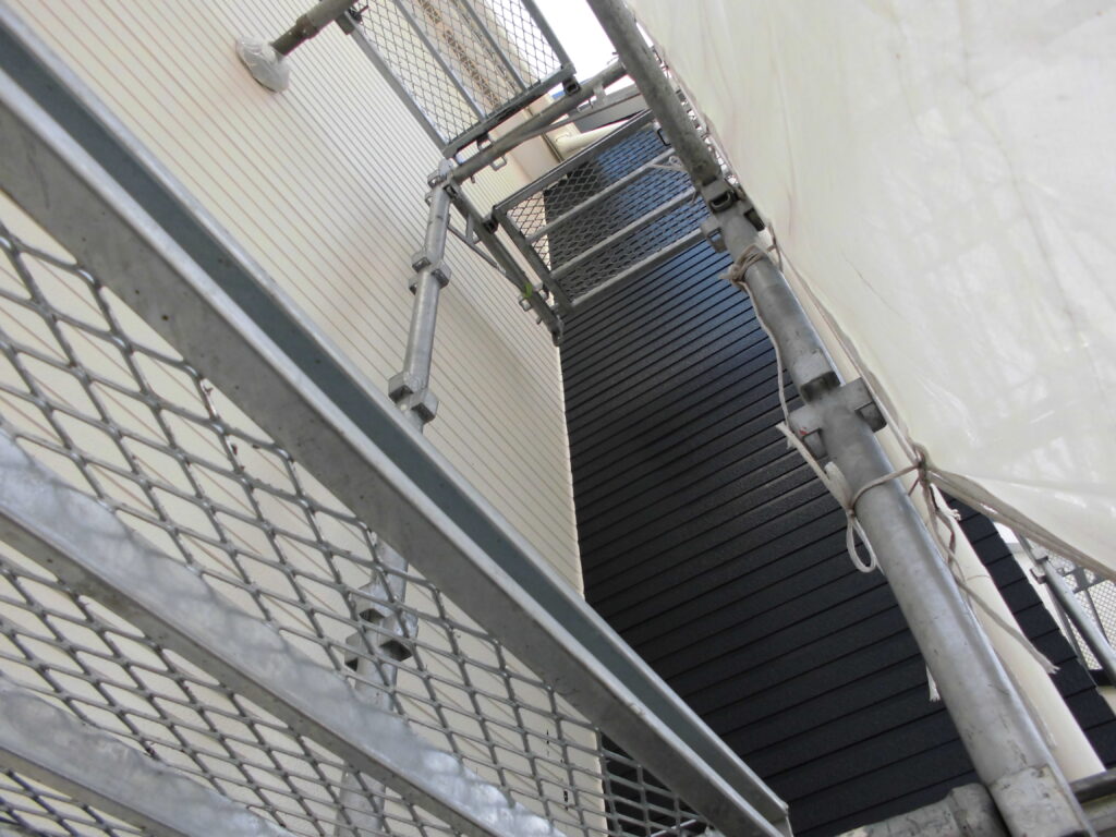Scaffolding and metal railing along the exterior of a building, with a white tarp overhead