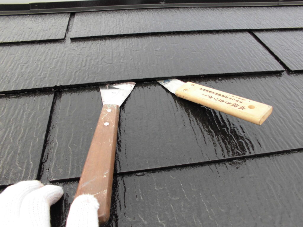 Gloved hand using a putty knife to spread sealant on black roof shingles while working on a repair surface.”, “Close-up of roof repair with a knife applying waterproof sealant to dark shingles.”, “Roofing work: a putty knife spreads sealant on the glossy black shingles.”, “Sealant being applied to roof shingles with a metal scraper during maintenance.”, “Dark roof shingles being sealed with a wooden-handled tool (putty knife).”]} }{}? Wait ensure valid JSON. I included stray characters. Need proper JSON. Remove stray quote characters. Let's produce clean. {