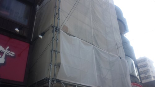 20140317 _084105 | 外壁塗装は神奈川県横浜市の塗装職人 Building under construction wrapped in white tarps with metal scaffolding along a city street.