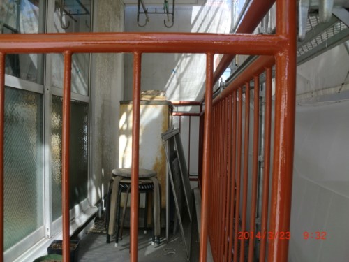 CIMG0383 | 外壁塗装は神奈川県横浜市の塗装職人 Narrow walkway between walls framed by red metal railing; clutter includes a stool, a wooden box, and a metal panel leaning against the wall.