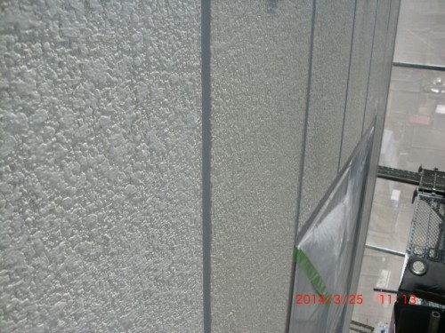 CIMG0385 | 外壁塗装は神奈川県横浜市の塗装職人 Close-up of textured wall panels with vertical seams and a glass-windowed area on the right side.