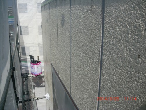 CIMG0386 | 外壁塗装は神奈川県横浜市の塗装職人 Narrow construction alley between scaffold and textured exterior wall; pink and white container sits on a platform in the background.