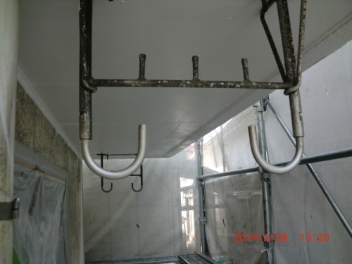 CIMG0400 | 外壁塗装は神奈川県横浜市の塗装職人 Underside of a suspended scaffolding platform with metal hooks and frame in a plastic-covered construction area.