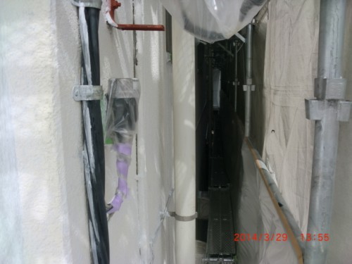 CIMG0405 | 外壁塗装は神奈川県横浜市の塗装職人 Narrow construction passage between walls with exposed pipes, scaffolding, and plastic sheeting along the sides.