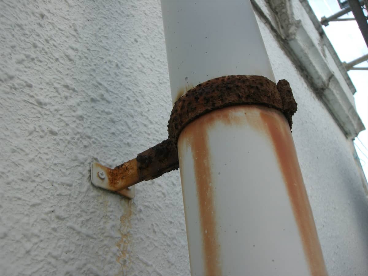 CIMG1357stainless | 外壁塗装は神奈川県横浜市の塗装職人 Rusted metal pipe attached to a white textured wall with brown rust streaks running down the surface.