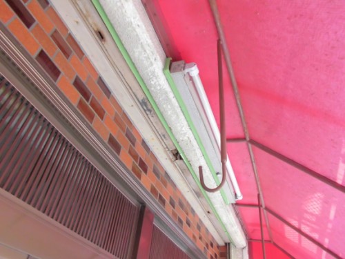 CIMG1382 | 外壁塗装は神奈川県横浜市の塗装職人 Outdoor storefront wall with a white fluorescent tube light under a pink canopy over brick wall with green trim.