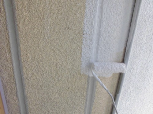 CIMG1387 | 外壁塗装は神奈川県横浜市の塗装職人 Paint roller applying white paint along a textured wall seam; beige left side, white right side