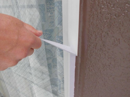 CIMG1397 | 外壁塗装は神奈川県横浜市の塗装職人 Hand pulling back a thin white protective film from a glass window pane.