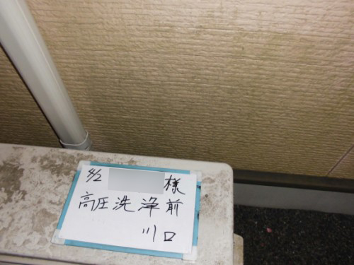 Maintenance tag attached to a surface reading'before high-pressure cleaning' (高圧洗浄前) in Japanese, taped to a white ledge near a wall.