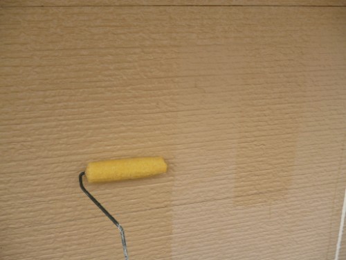 Small yellow foam paint roller resting on a wooden surface.