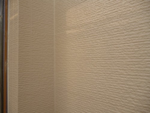 Texture close-up of beige textured walls meeting at a corner, showing horizontal grooves and a slight shadow.